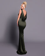 Woman wearing a green evening gown with a draped back design on a gray background