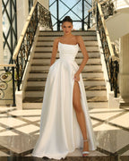 Woman in a white strapless gown with a high slit standing on a staircase.