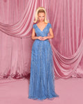 Woman in a blue evening gown standing against a pink curtain backdrop