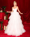 Woman in a white wedding dress standing in front of a red curtain