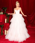 Woman in a white wedding dress standing in front of a red curtain