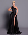 Woman wearing a black one-shoulder gown with a slit on a gray background