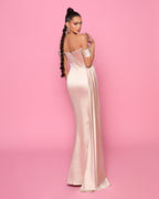 Woman in a long, elegant dress against a pink background