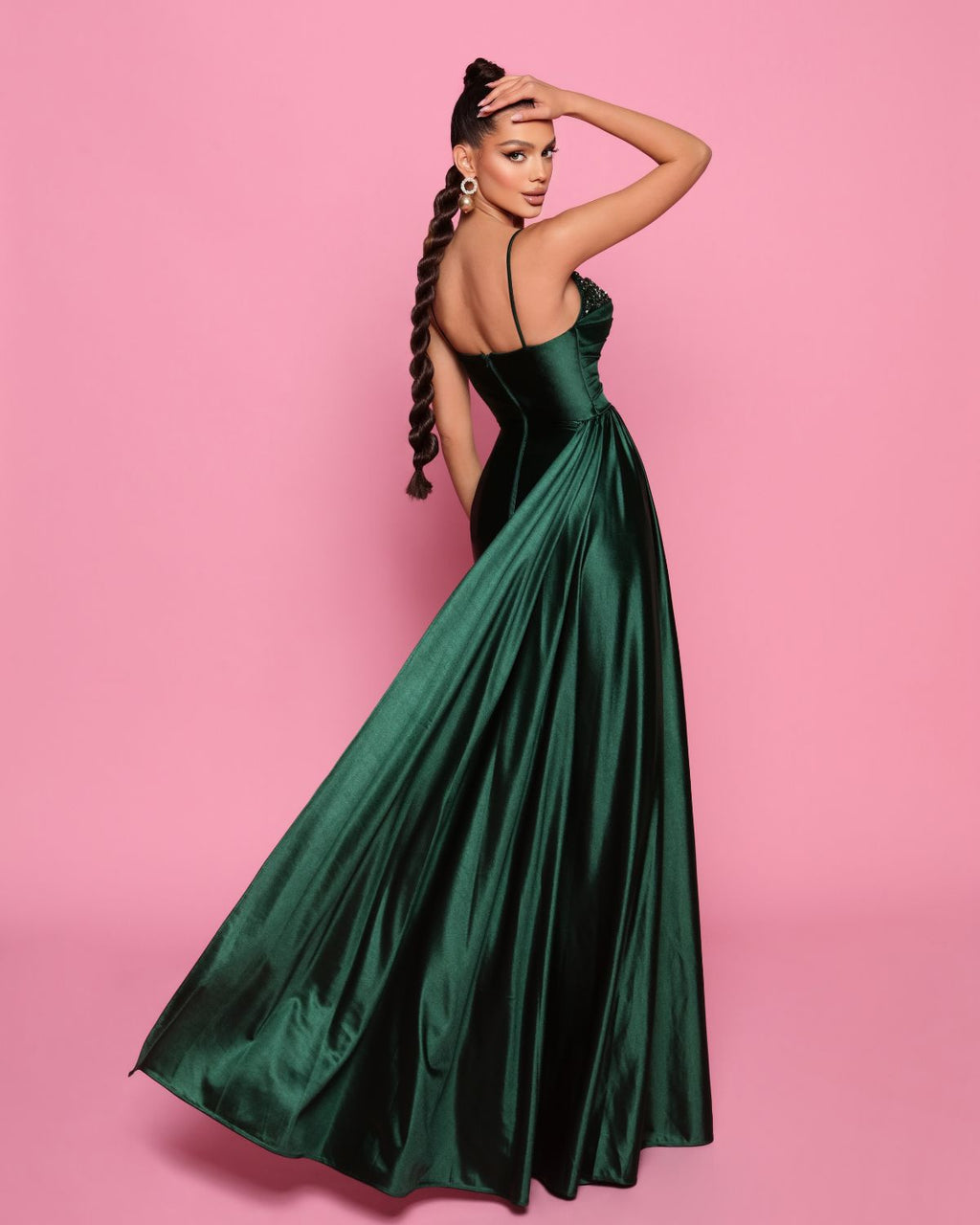 Woman in a green evening gown against a pink background
