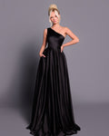 Woman wearing a black one-shoulder gown against a gray background