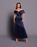 Woman wearing a navy off-shoulder gown against a gray background