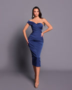 Woman wearing a blue off-shoulder dress against a gray background