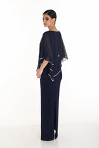 Woman wearing a navy blue evening gown with a matching cape on a white background