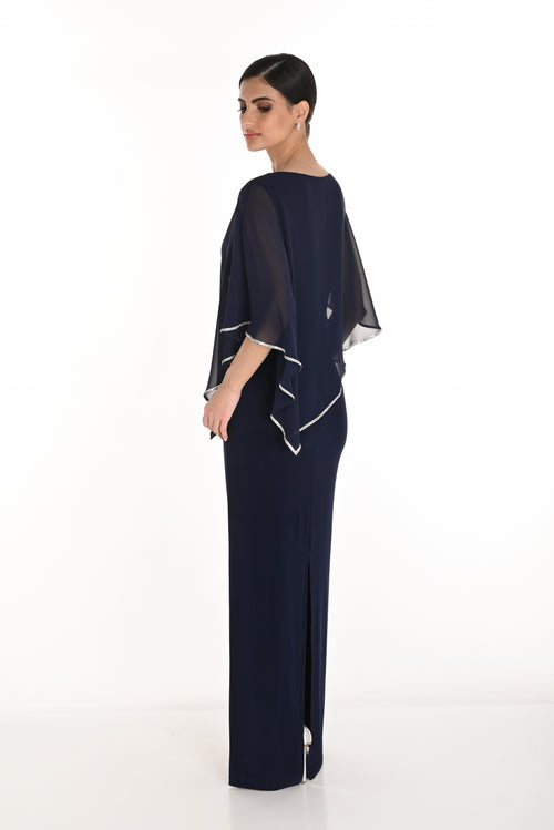 Woman wearing a navy blue evening gown with a matching cape on a white background