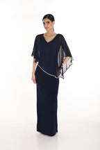 Woman wearing a navy evening gown with sheer sleeves on a white background
