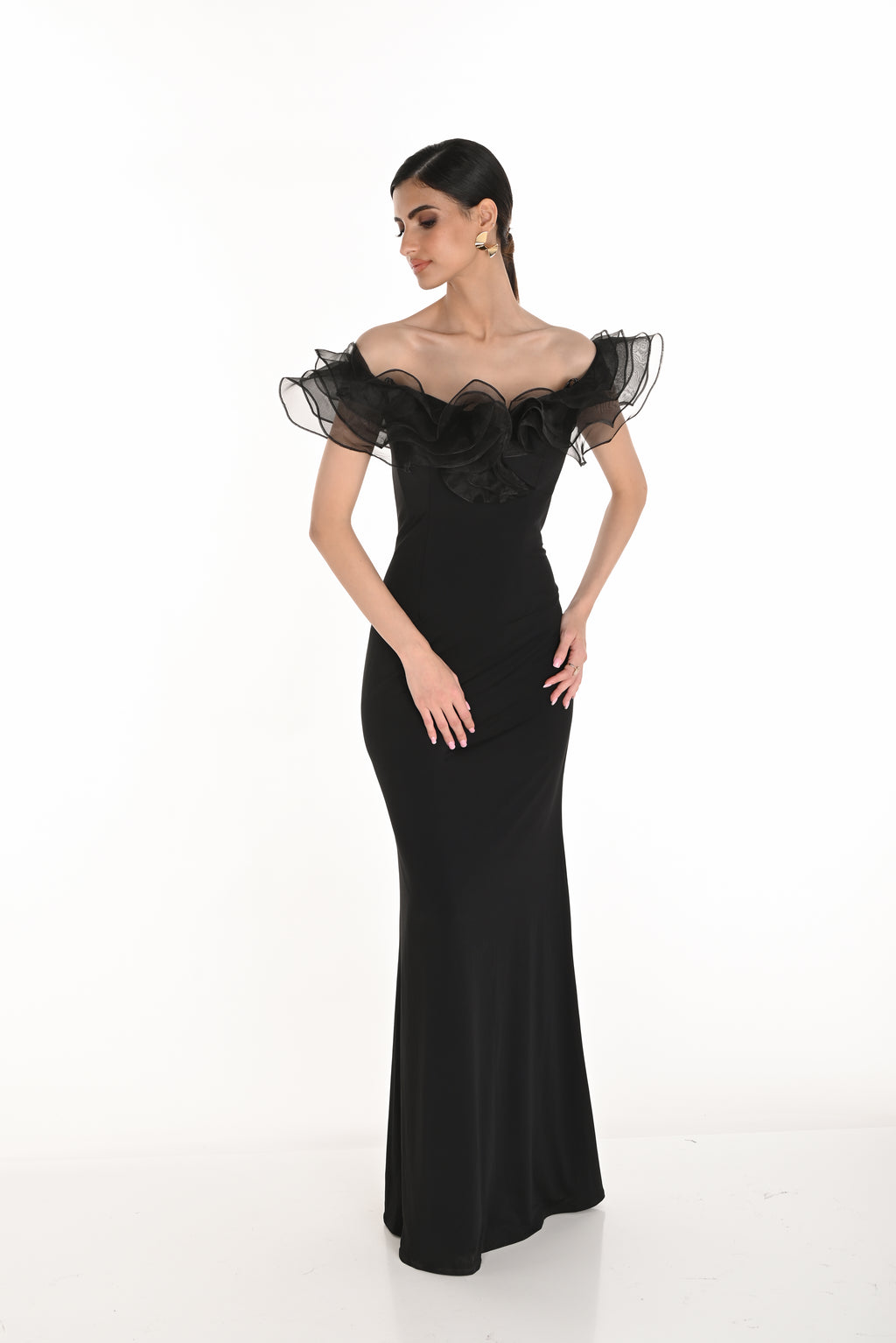 Woman wearing a black evening gown with sheer sleeves on a white background