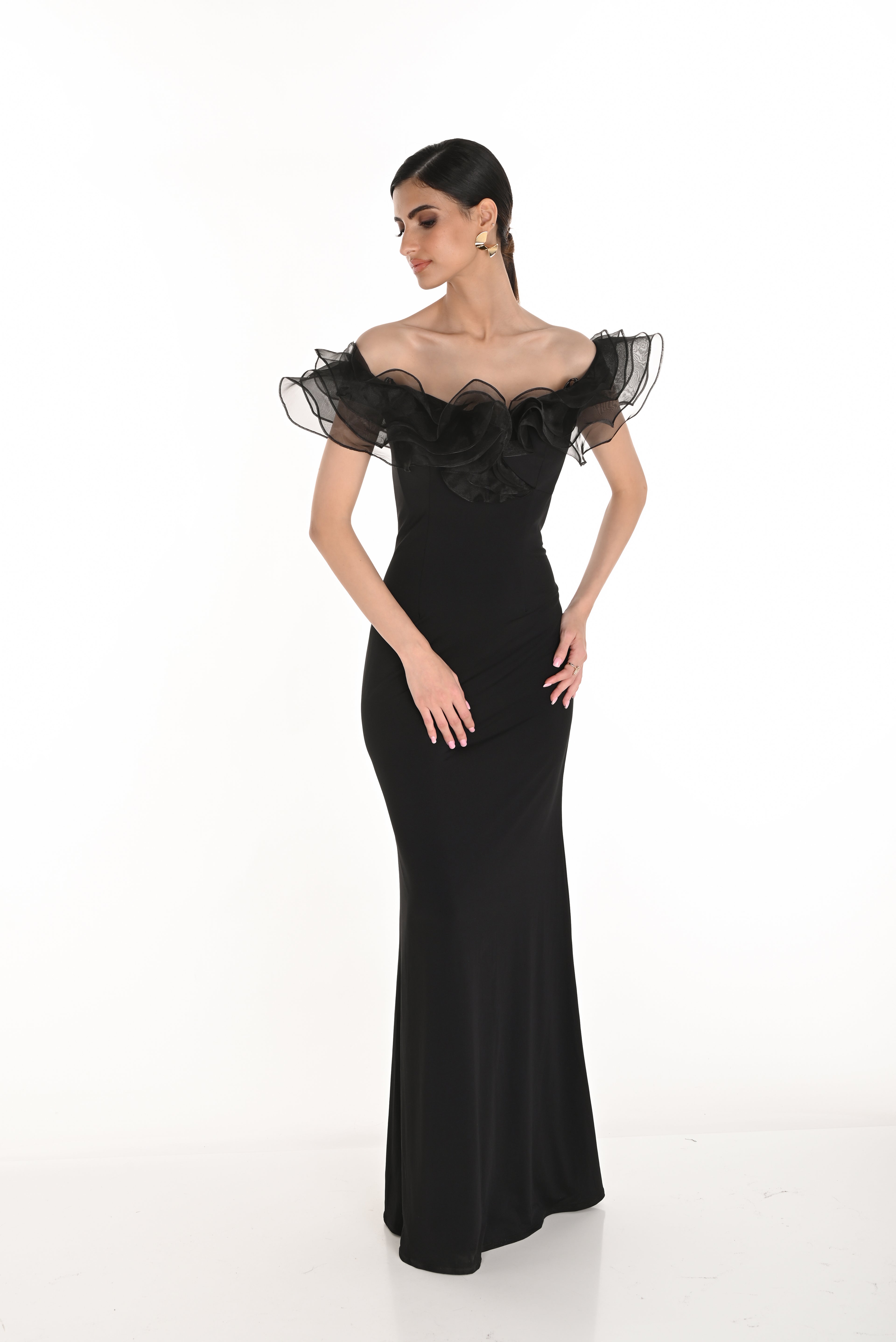 Woman wearing a black evening gown with sheer sleeves on a white background