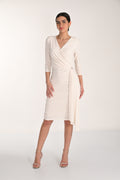 Woman wearing a white wrap dress on a plain background