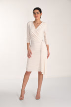 Woman wearing a white wrap dress on a plain background