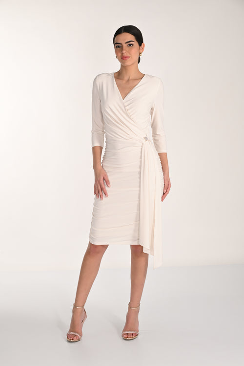 Woman wearing a white wrap dress on a plain background