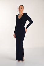 Woman wearing a black long-sleeve gown with a slit on a white background