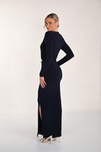 Woman wearing a black long-sleeve dress with a slit on a white background