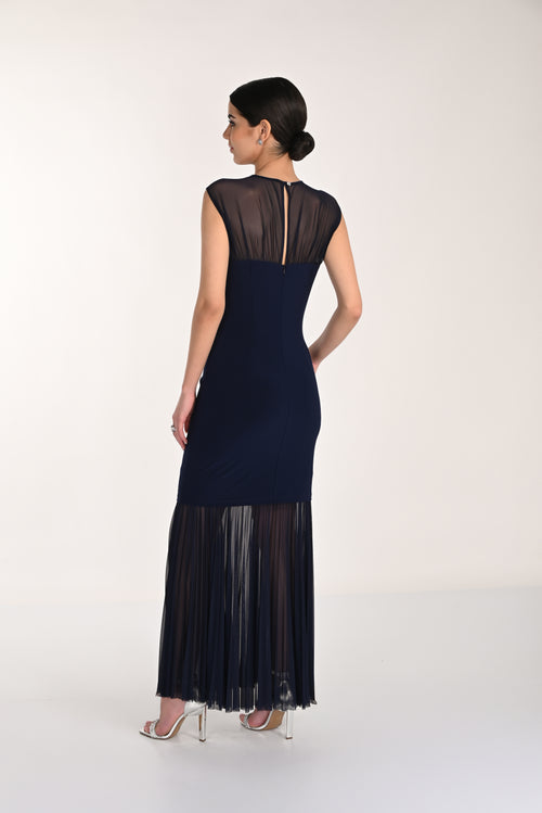 Woman wearing a navy dress with sheer black details on a white background