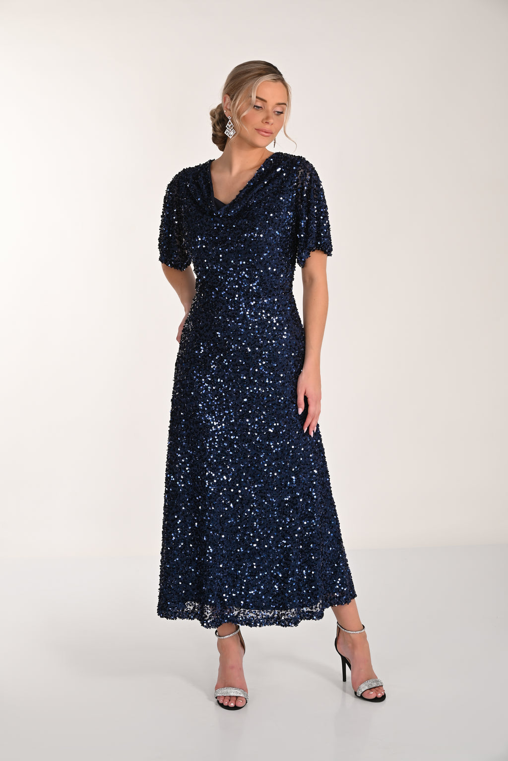 Woman wearing a navy sequin dress on a white background