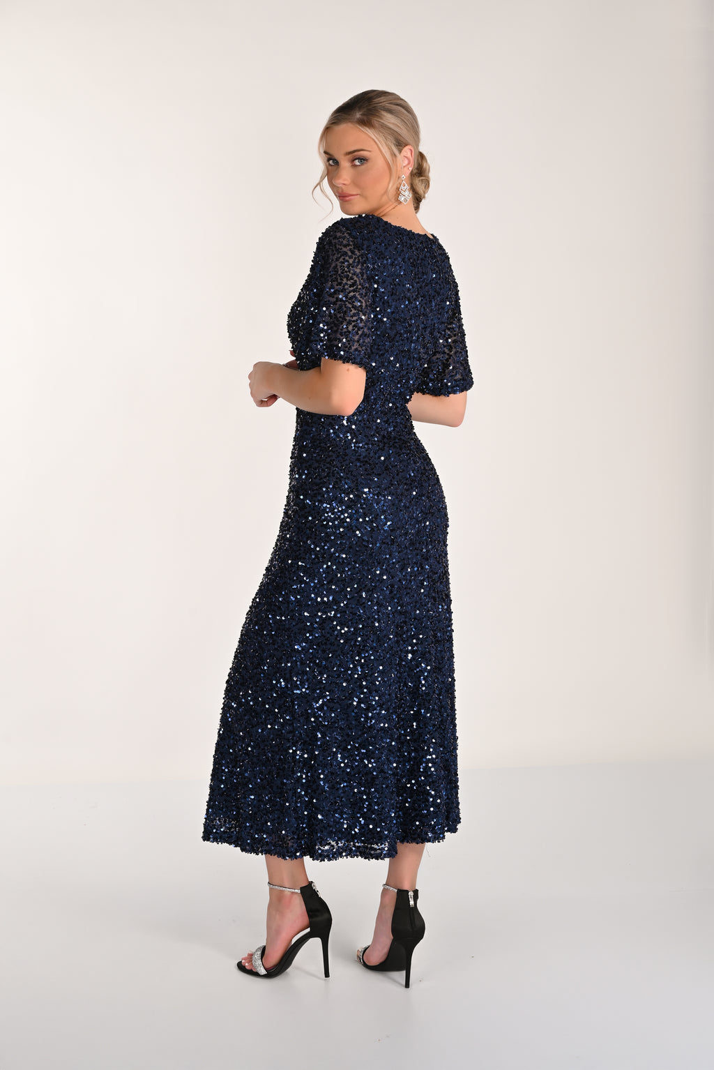 Woman wearing a navy blue sequin dress on a white background