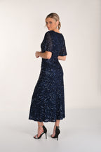 Woman wearing a navy blue sequin dress on a white background