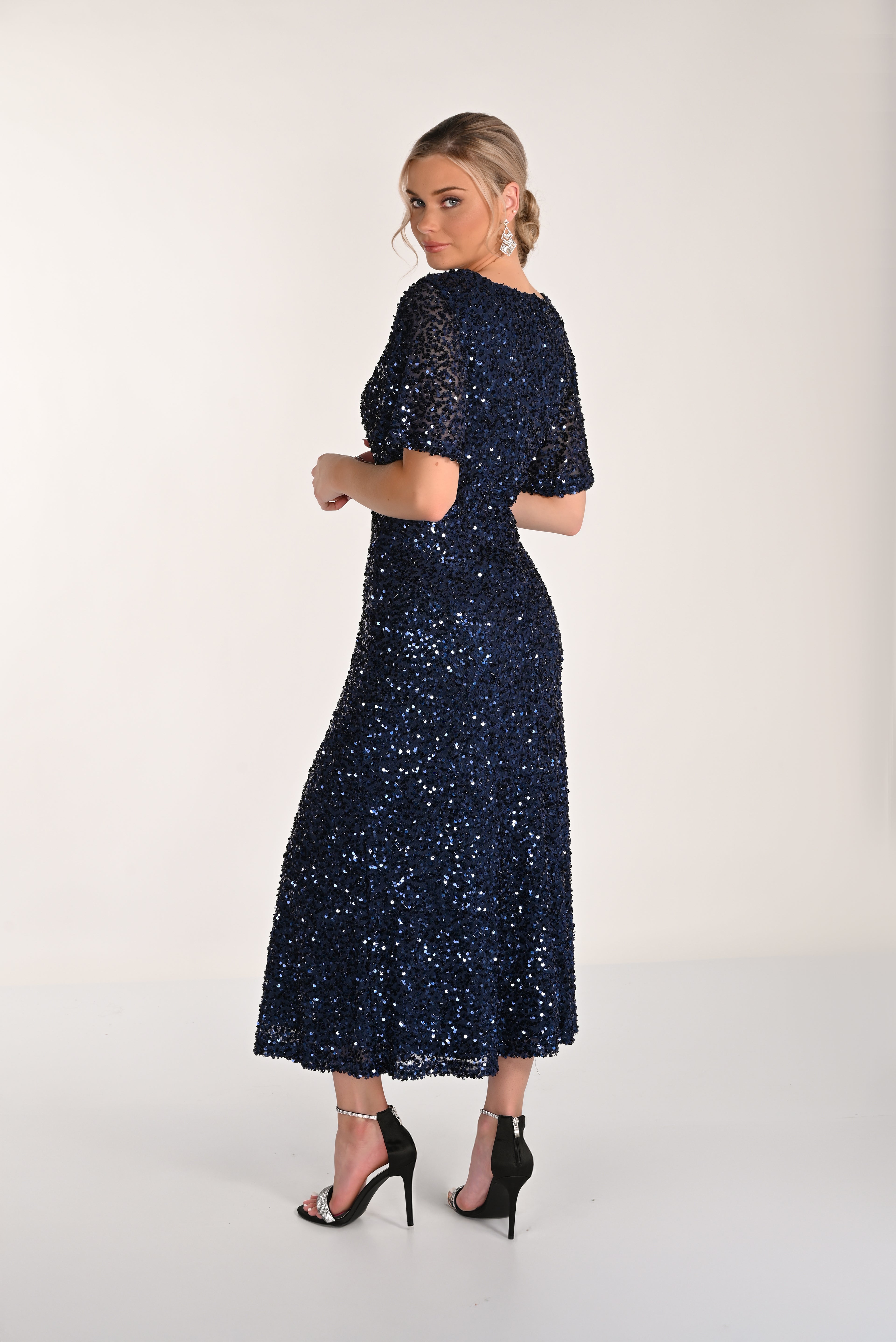 Woman wearing a navy blue sequin dress on a white background
