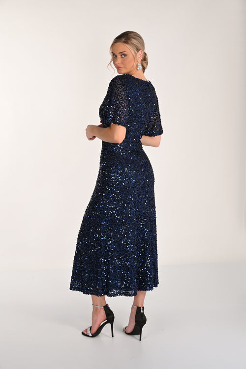 Woman wearing a navy blue sequin dress on a white background