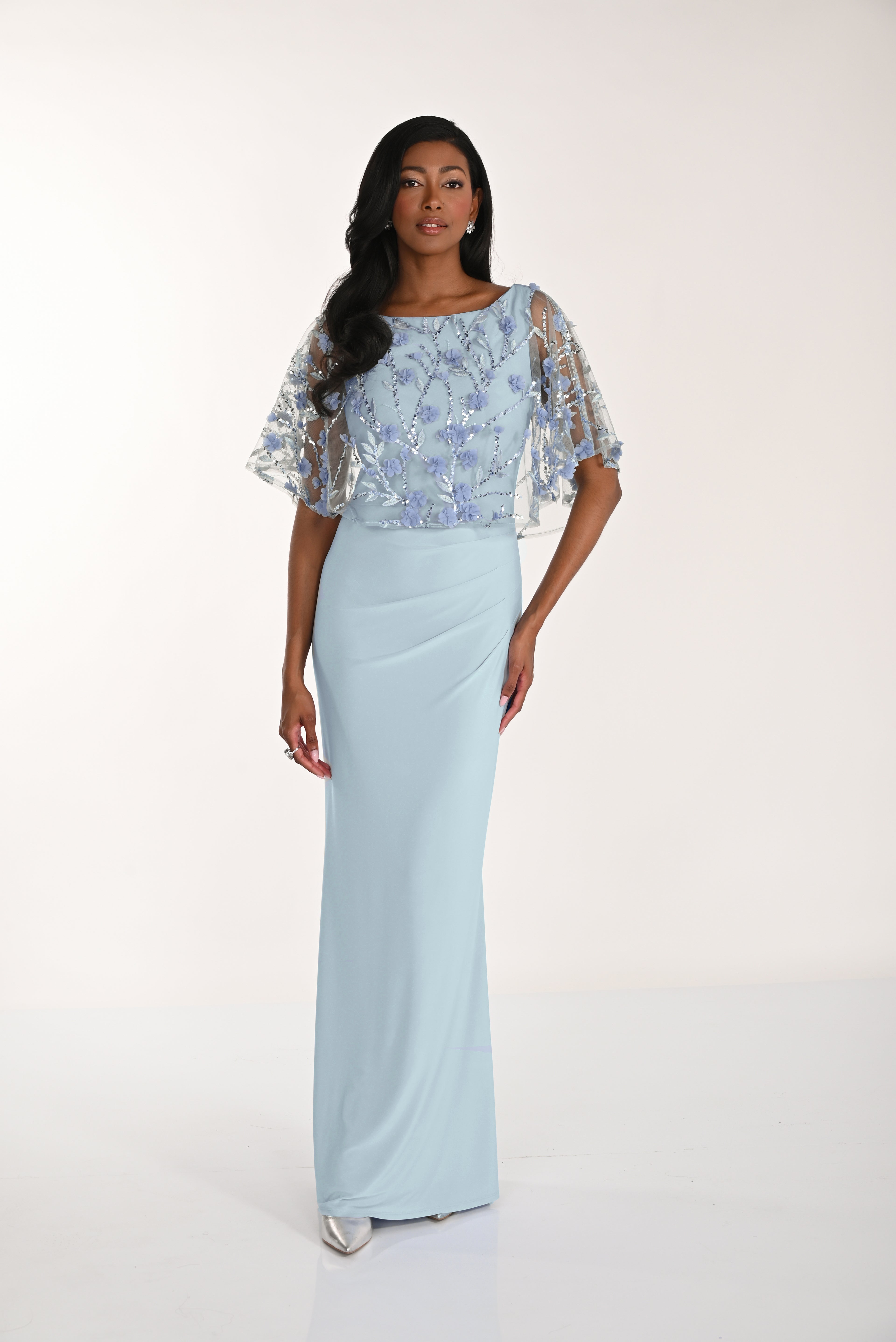 Woman wearing a light blue dress with floral embellishments on a white background