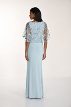 Woman wearing a light blue evening gown with floral lace top on a white background