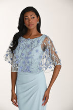 Woman wearing a light blue dress with floral embellishments on a white background