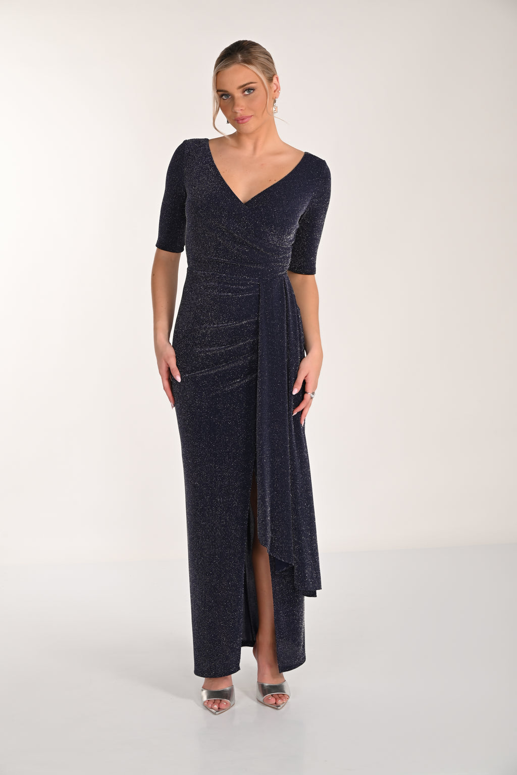 Woman wearing a dark blue evening gown with a V-neckline and quarter sleeves on a white background