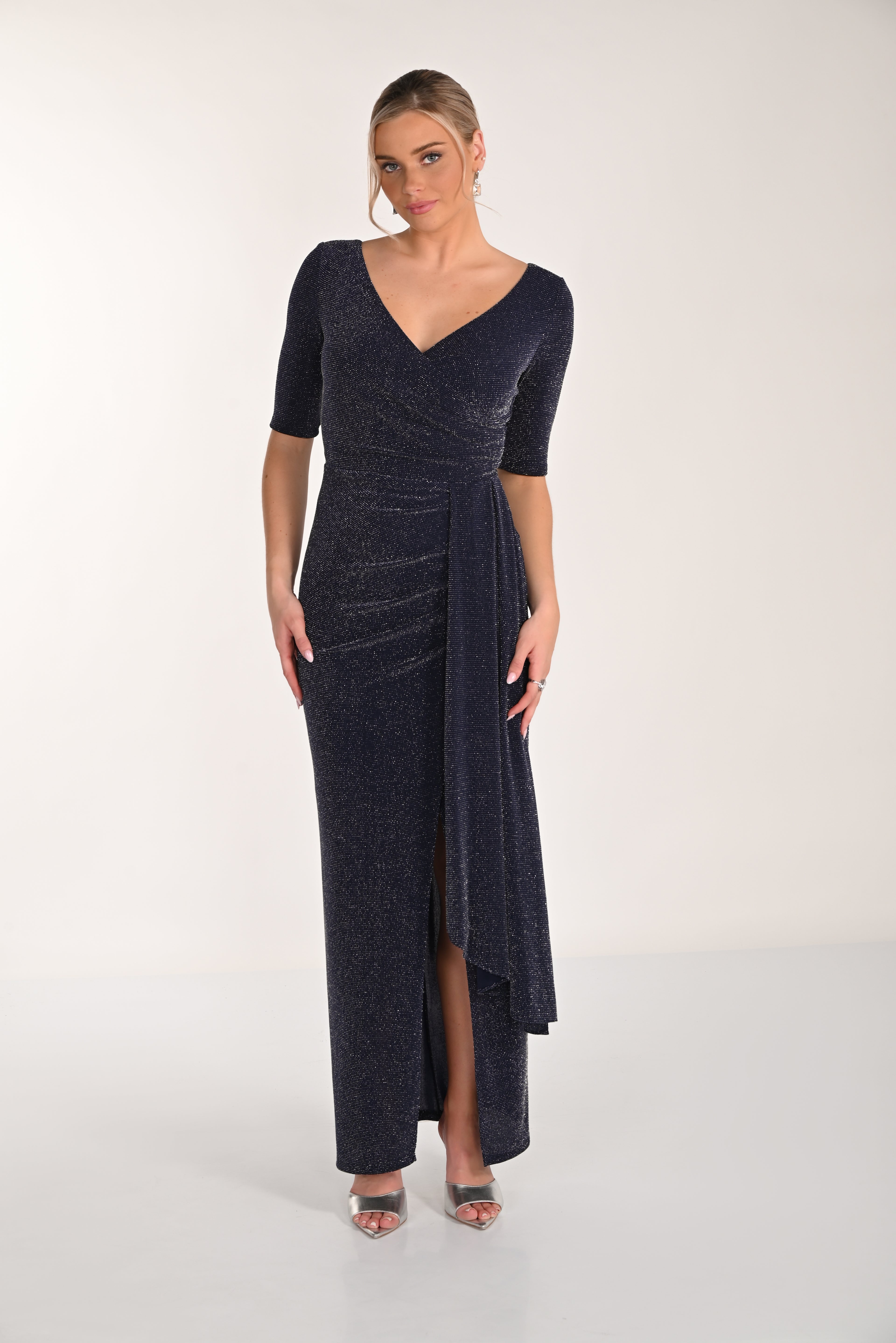 Woman wearing a dark blue evening gown with a V-neckline and quarter sleeves on a white background