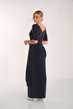 Woman wearing a dark blue evening gown with a slit on a white background