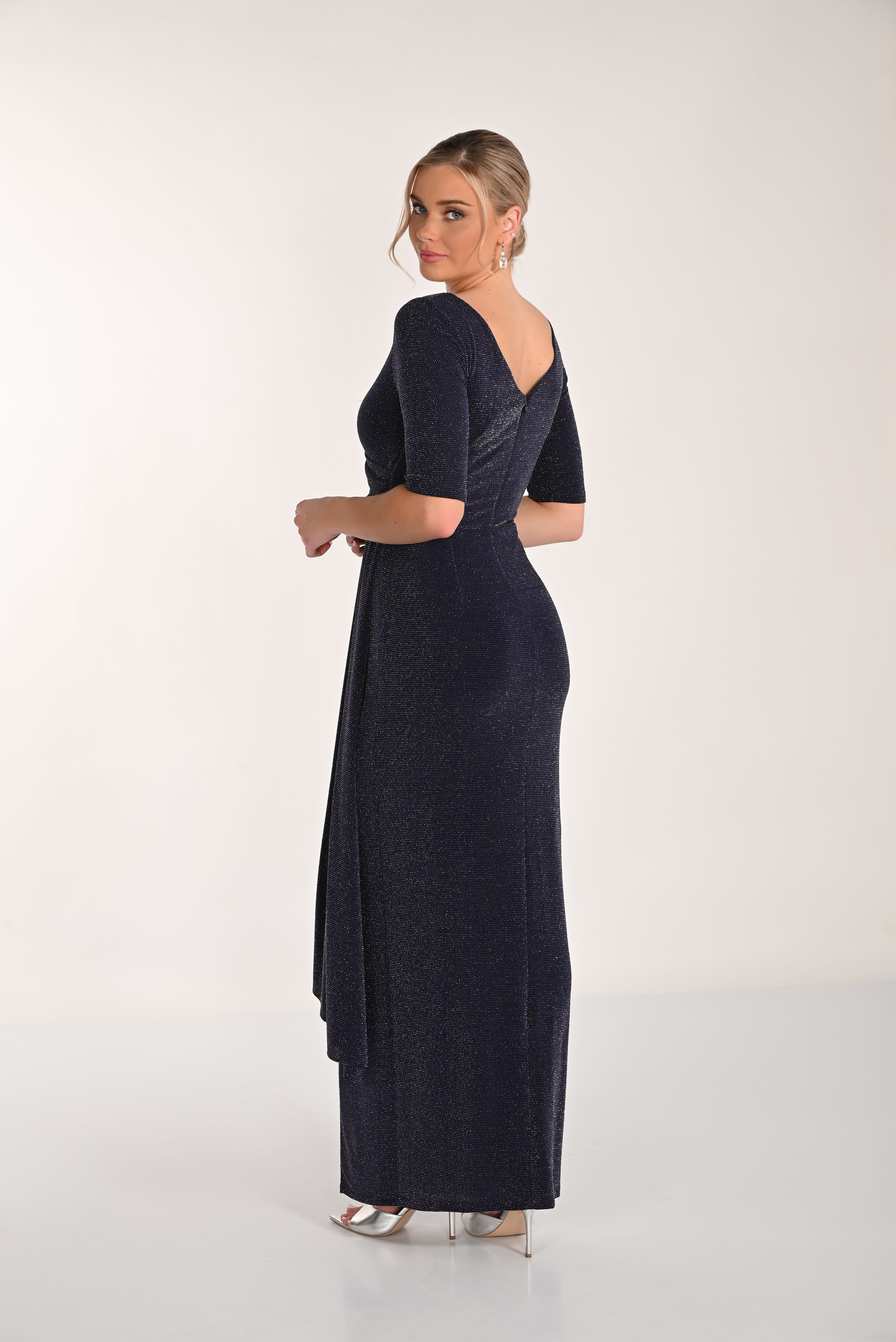Woman wearing a dark blue evening gown with a slit on a white background