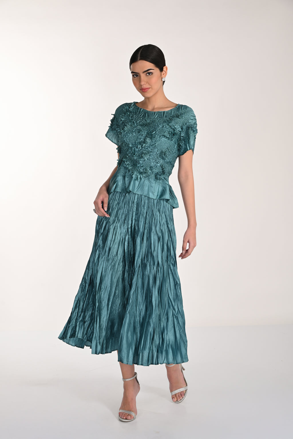 Woman wearing a teal dress with a textured pattern on a white background
