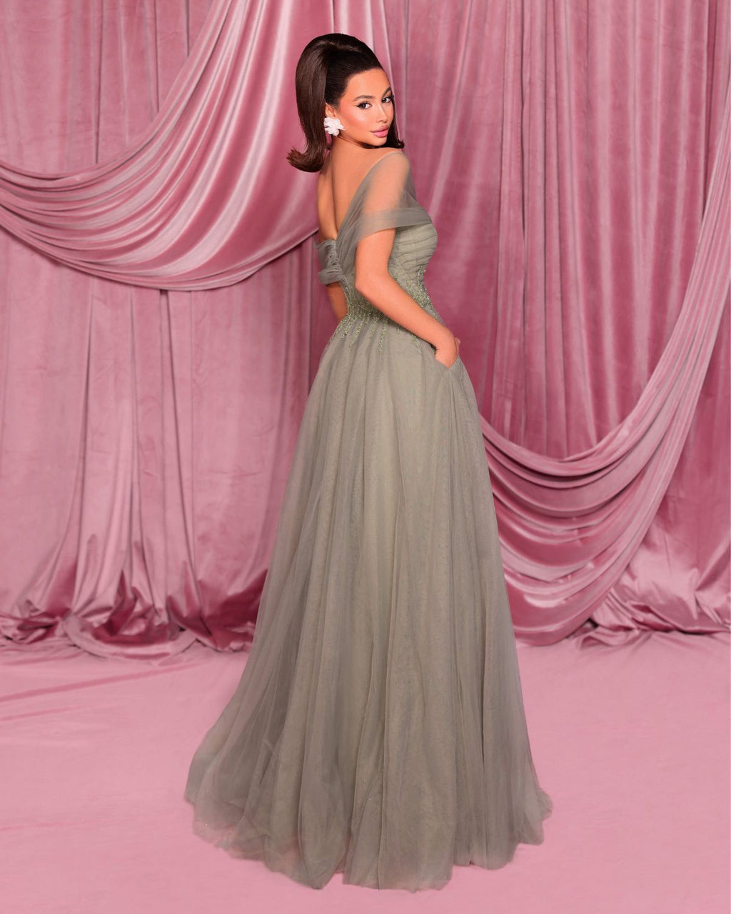 Woman in a gray evening gown against a pink draped curtain backdrop