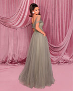 Woman in a gray evening gown against a pink draped curtain backdrop