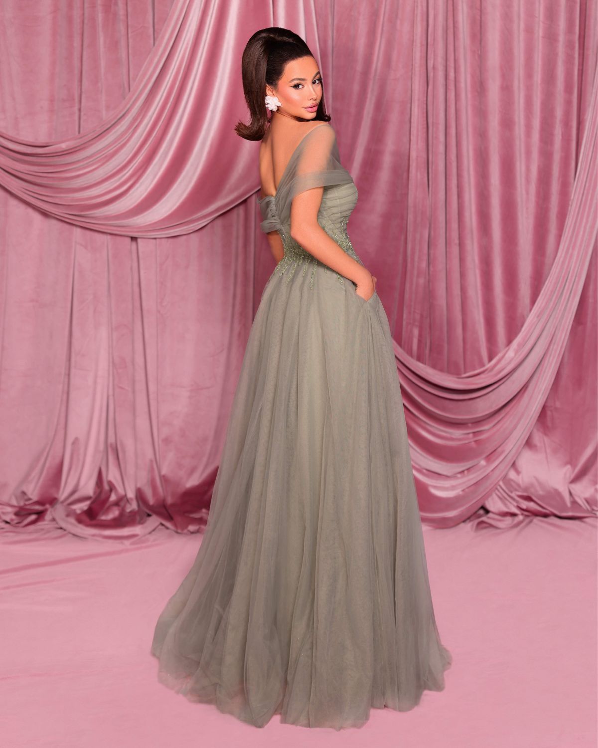 Woman in a gray evening gown against a pink draped curtain backdrop