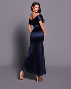Woman wearing a navy blue off-shoulder gown against a gray background
