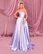 Woman in a strapless, light purple gown against a pink curtain backdrop