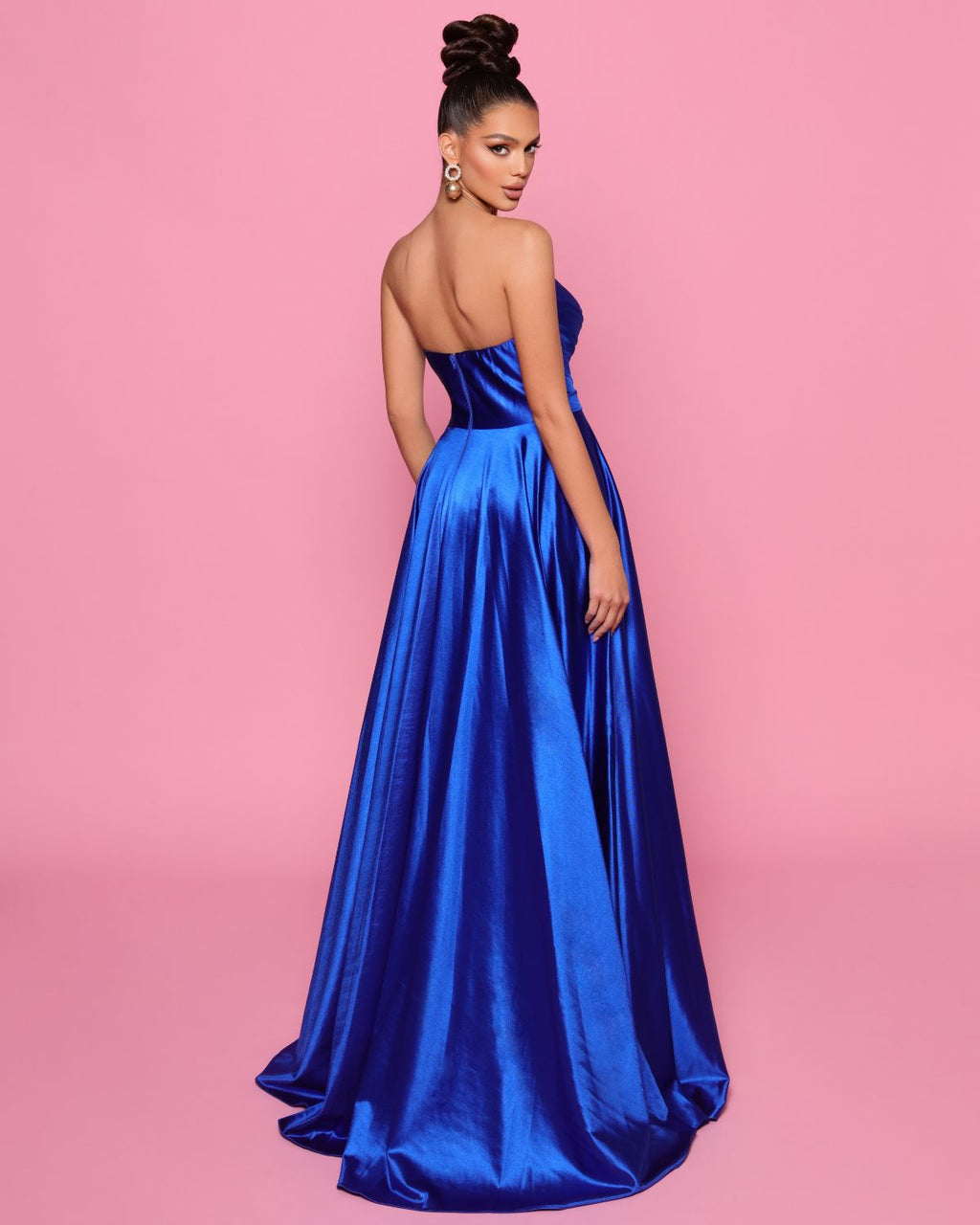 Woman wearing a blue strapless gown against a pink background