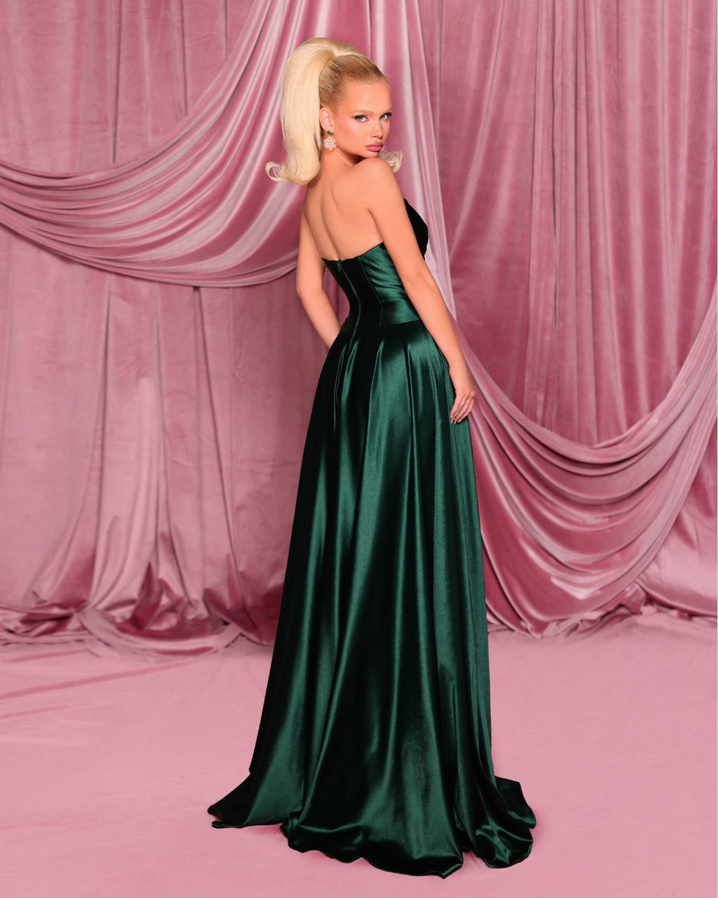 Woman in a green evening gown against a pink curtain backdrop