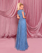 Woman in a blue evening gown standing in front of pink curtains