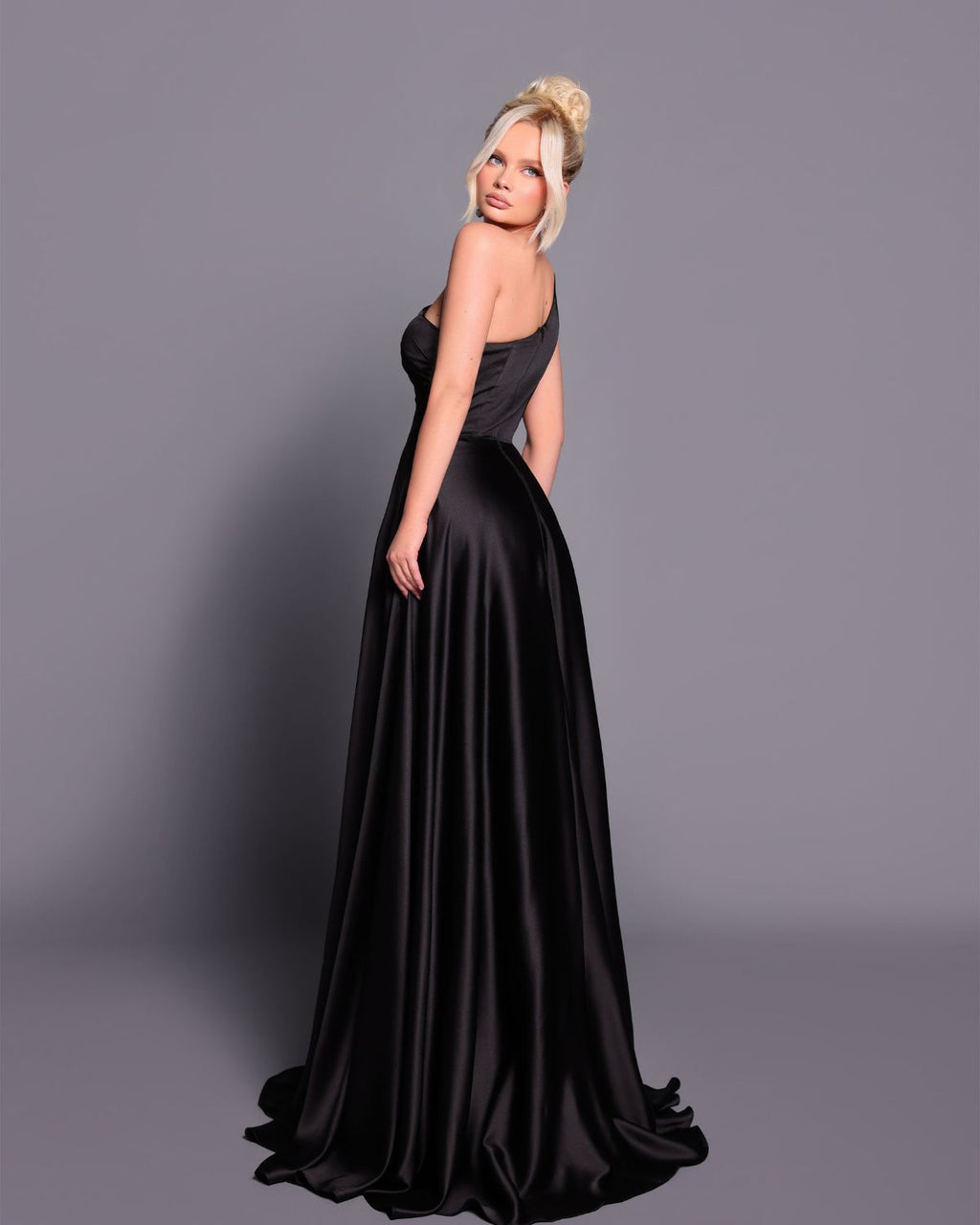 Woman wearing a black evening gown against a gray background