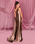 Woman in a gold evening gown standing against a pink draped curtain backdrop