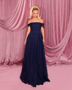 Woman in a navy blue evening gown against a pink curtain backdrop