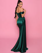 Woman wearing a green strapless gown against a pink background