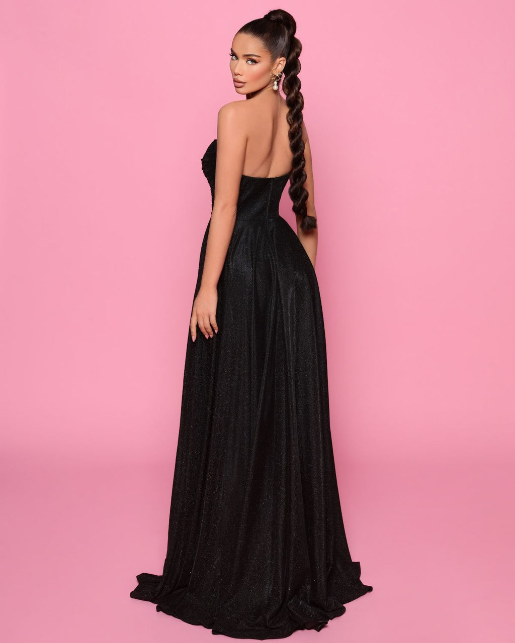 Woman in a black evening gown against a pink background