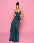 Woman wearing a teal strapless gown against a pink background