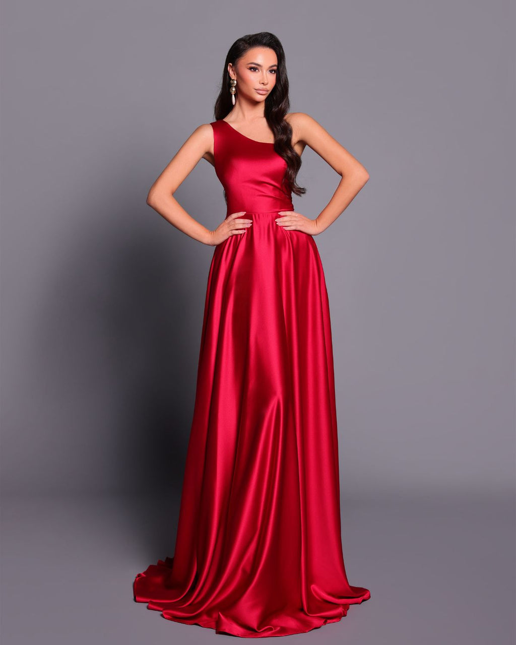 Woman wearing a red satin gown against a gray background
